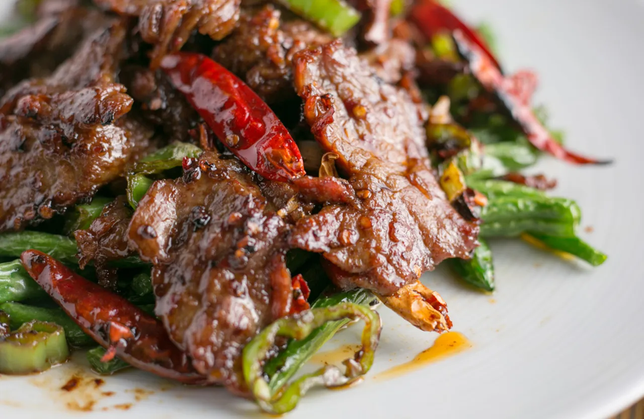 Close-up of seared beef with red chilies and green vegetables